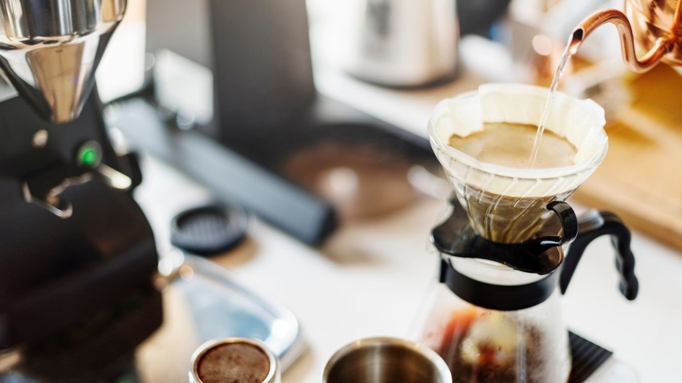 Cantinho do café decorado com cafeteira, xícaras, bandeja e acessórios organizados sobre aparador